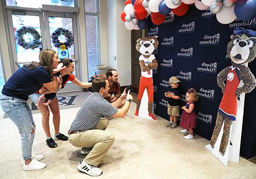 Family taking pictures of their kids in 校友 with cutouts of 南paw和Ms. Pawla.